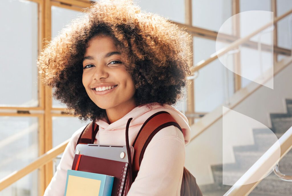 A happy mixed-race student smiles in the stairwell of a school. The ImageSource icon in white appears on the right of the frame.